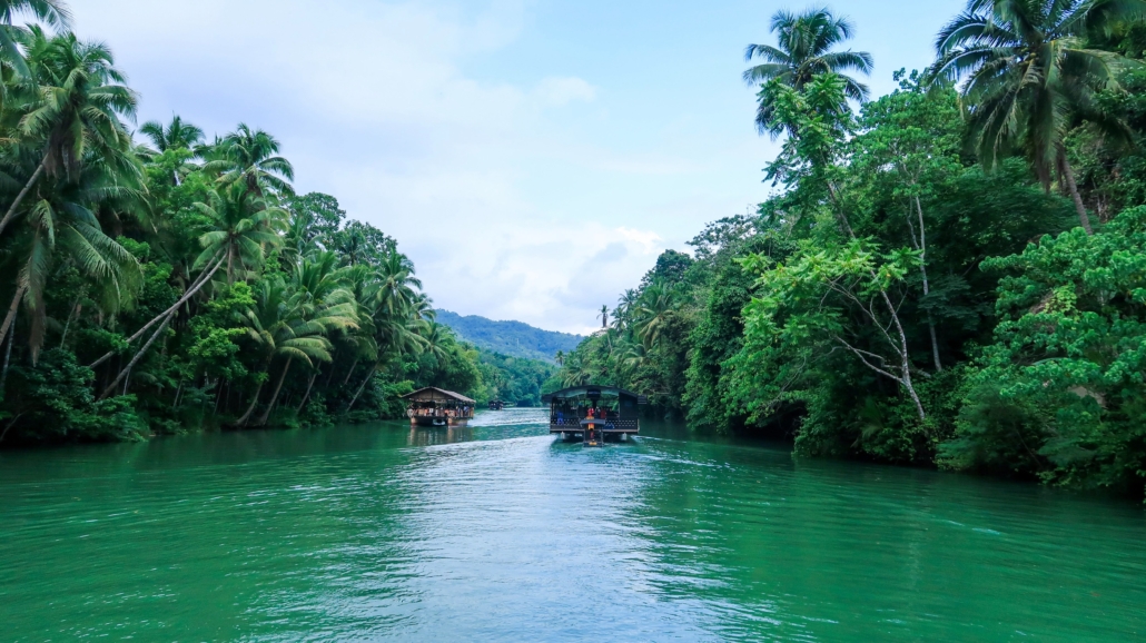 Vollbesetzte Boote auf dem grünen Loboc-River mit lauter Musik